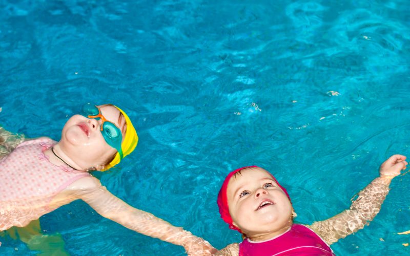 Two,Happy,Little,Girls,Learning,To,Swim,In,A,Pool